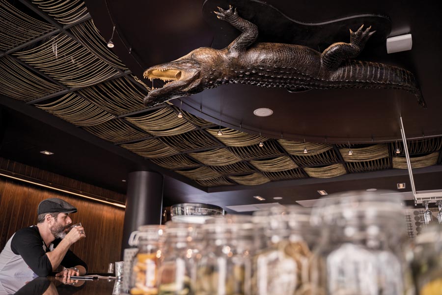 The dimmed and modern milieu of the bar and lounge area calls for cocktails. An inverted alligator on the ceiling offers that final Florida touch. Photo by Wyatt Kostygan.